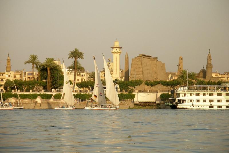 Feluccas sailing on the Nile at Luxor, with Luxor Temple and the town behind
