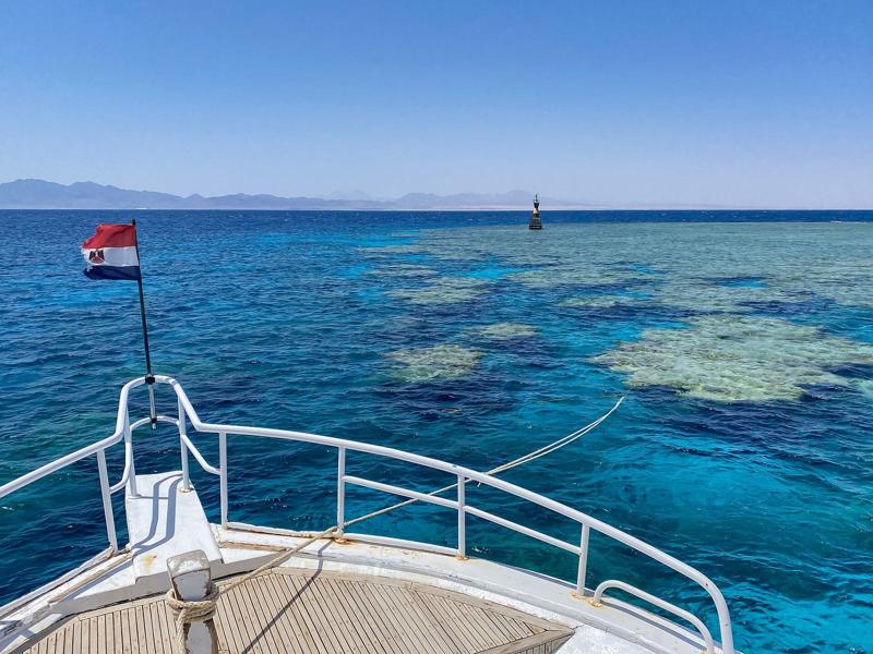 The bow of a dive boat flying the Egyptian flag above the coral of Middle Reef near Safaga